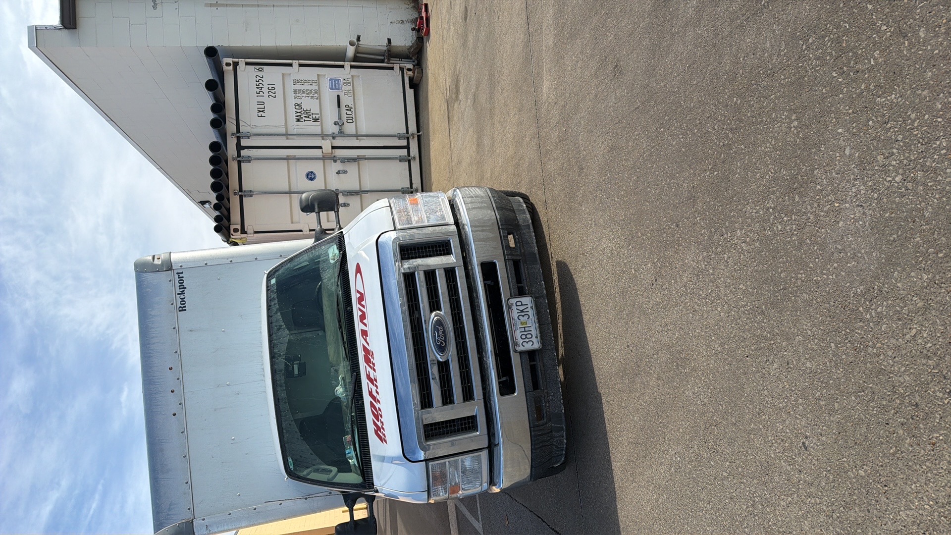 Plush Tow and Transport operator next to flatbed truck at sunset